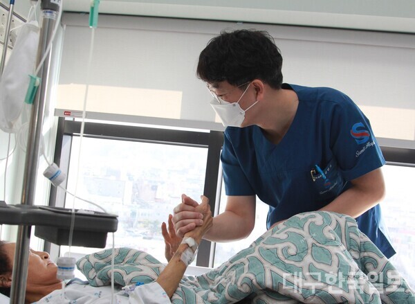 김만기 삼일병원 외과 과장이 담도암으로 투병을 하고 있는 장모(68)씨의 손을 잡고 문진을 하고 있다. 이들의 인연은 2014년 대학병원에서부터 이어져 오고 있다.